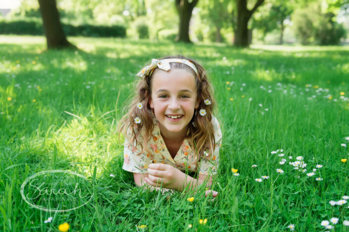 Meisje dat haar communie doet ligt lachend in het gras.